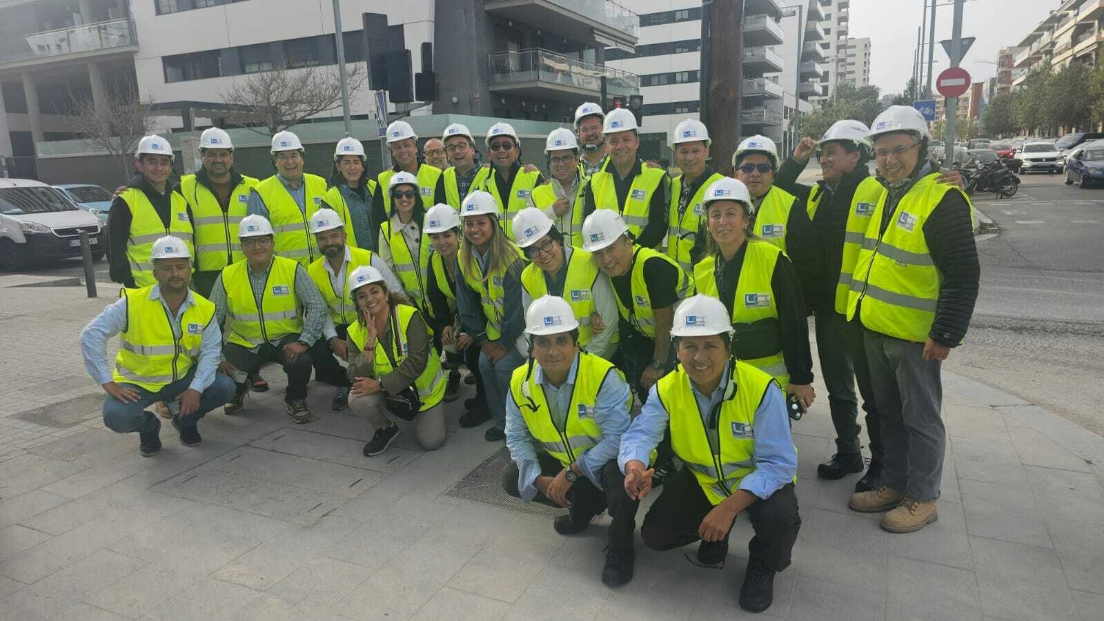 Grupo de cerca de treinta profesionales con cascos y chalecos reflectantes marcados LCI Chile, durante una visita a obra en Santiago.